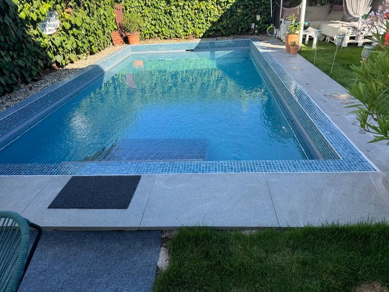 Pool mit Mosaikkante, Plattenrand und Rasen