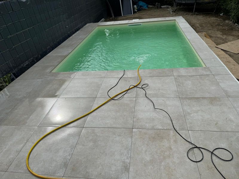 Pool mit heller Plattenterrasse nach dem Befüllen