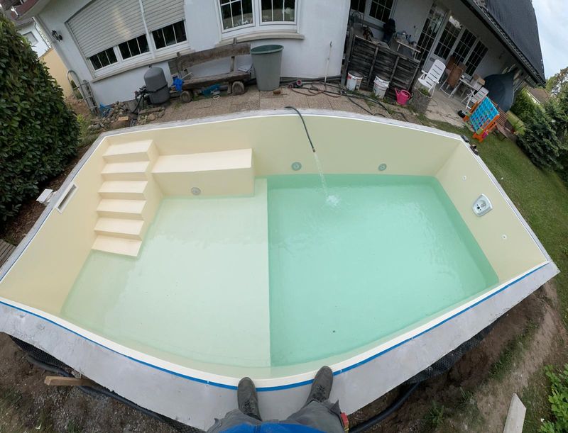 Becken mit heller Folie und eingebauter Treppe beim Befüllen
