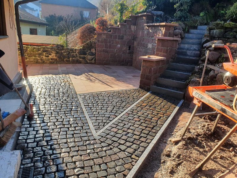 Hof aus Kopfsteinpflaster mit Sandsteinmauer und Treppe
