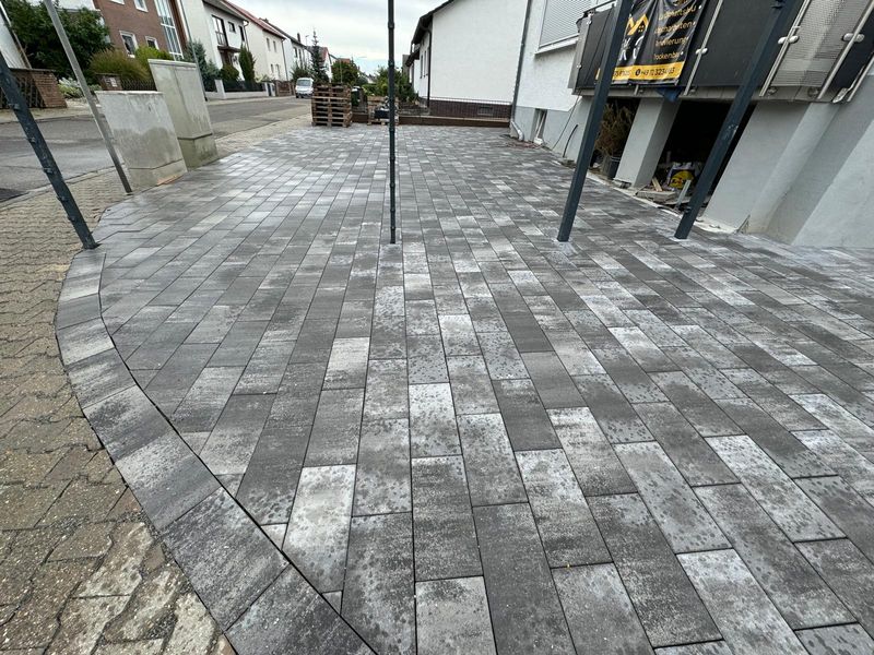 Hofeinfahrt mit grauem Pflaster in Bogenform